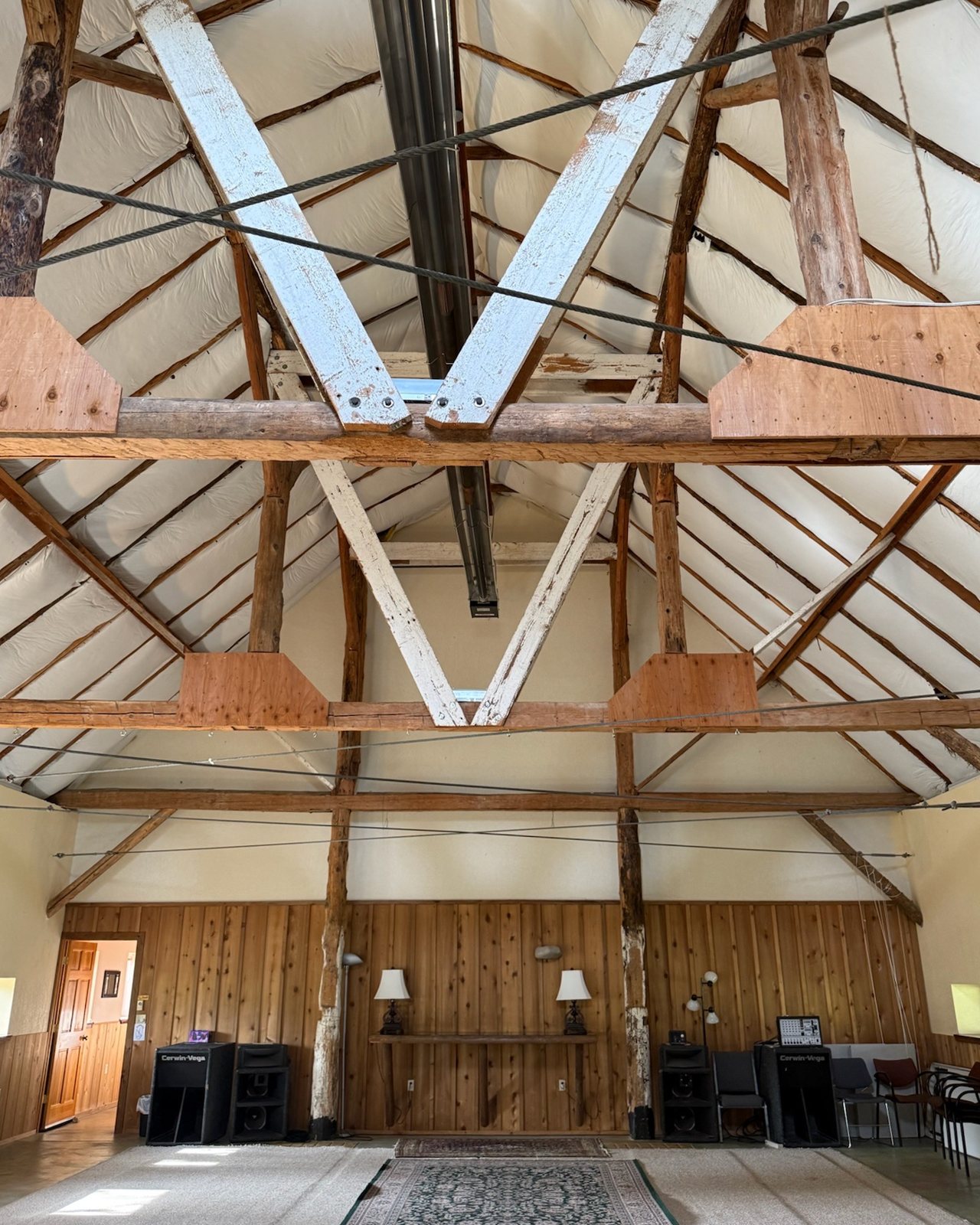 The Old Dairy Barn: tall open trusses above cedar-paneled walls and rugs on the floor